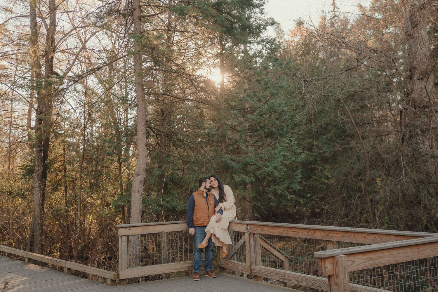 A romantic sunset moment on a wooden bridge surrounded by autumn trees.