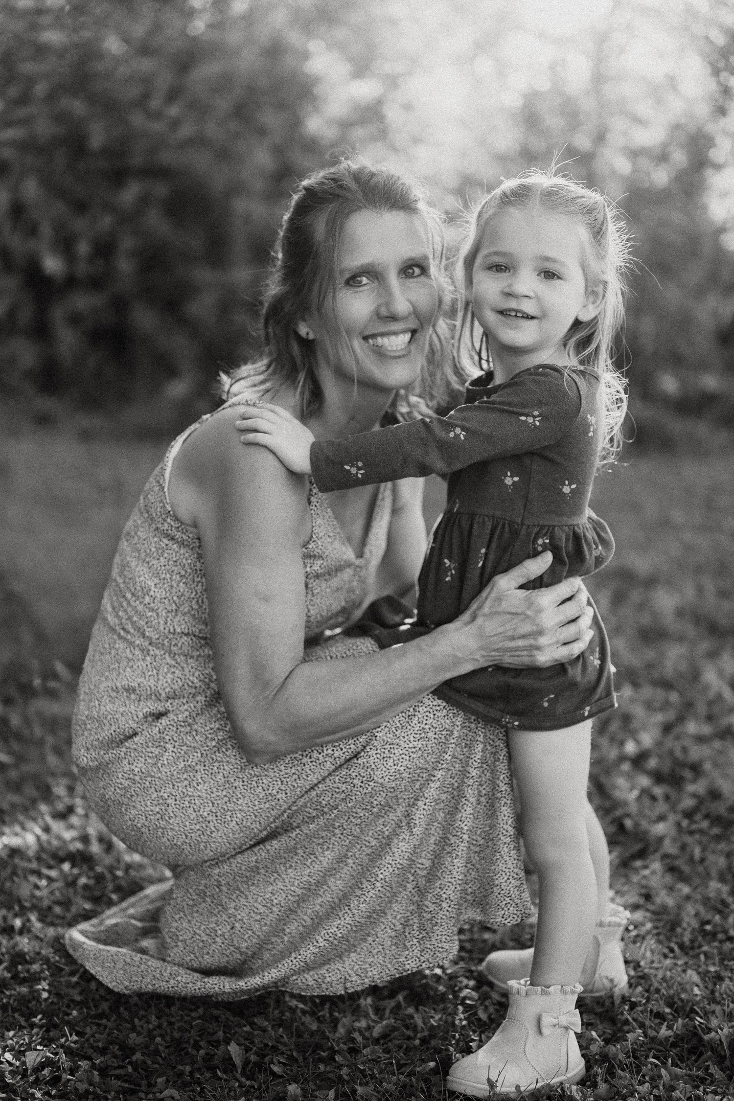 A series of black and white photos showing tender moments between a parent and child sitting together outdoors.