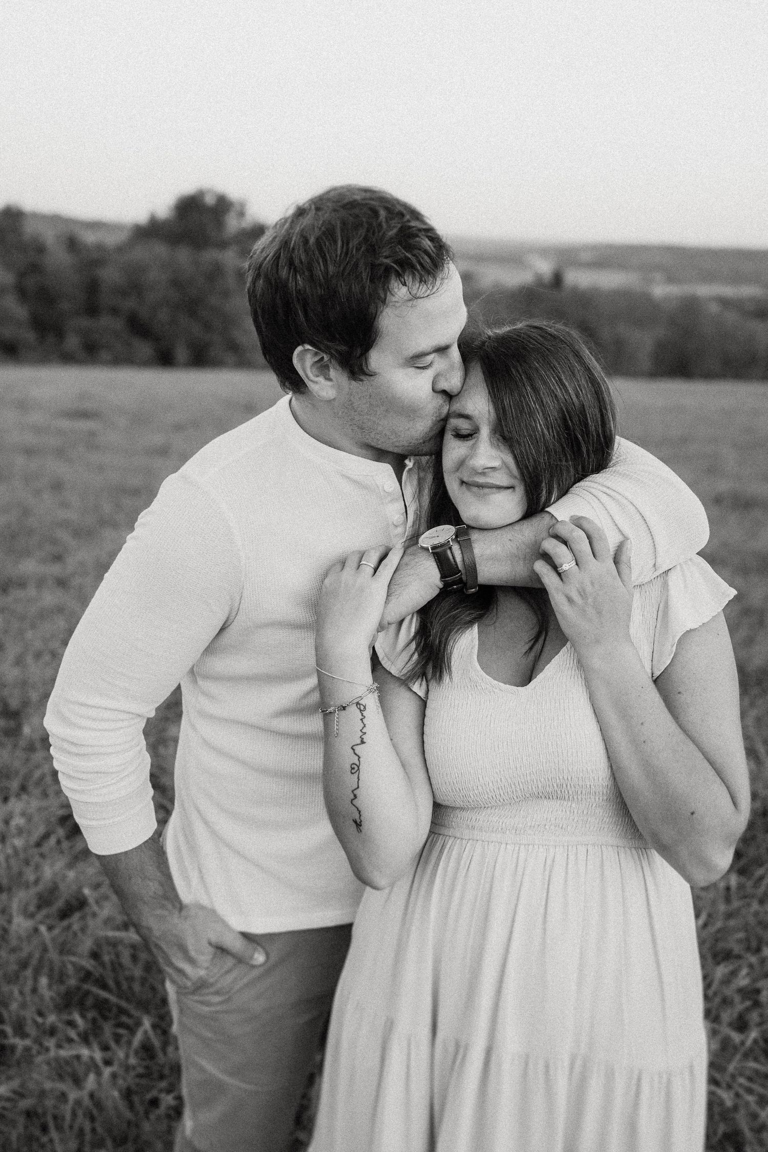 Intimate black and white portrait of couple embracing in a meadow.