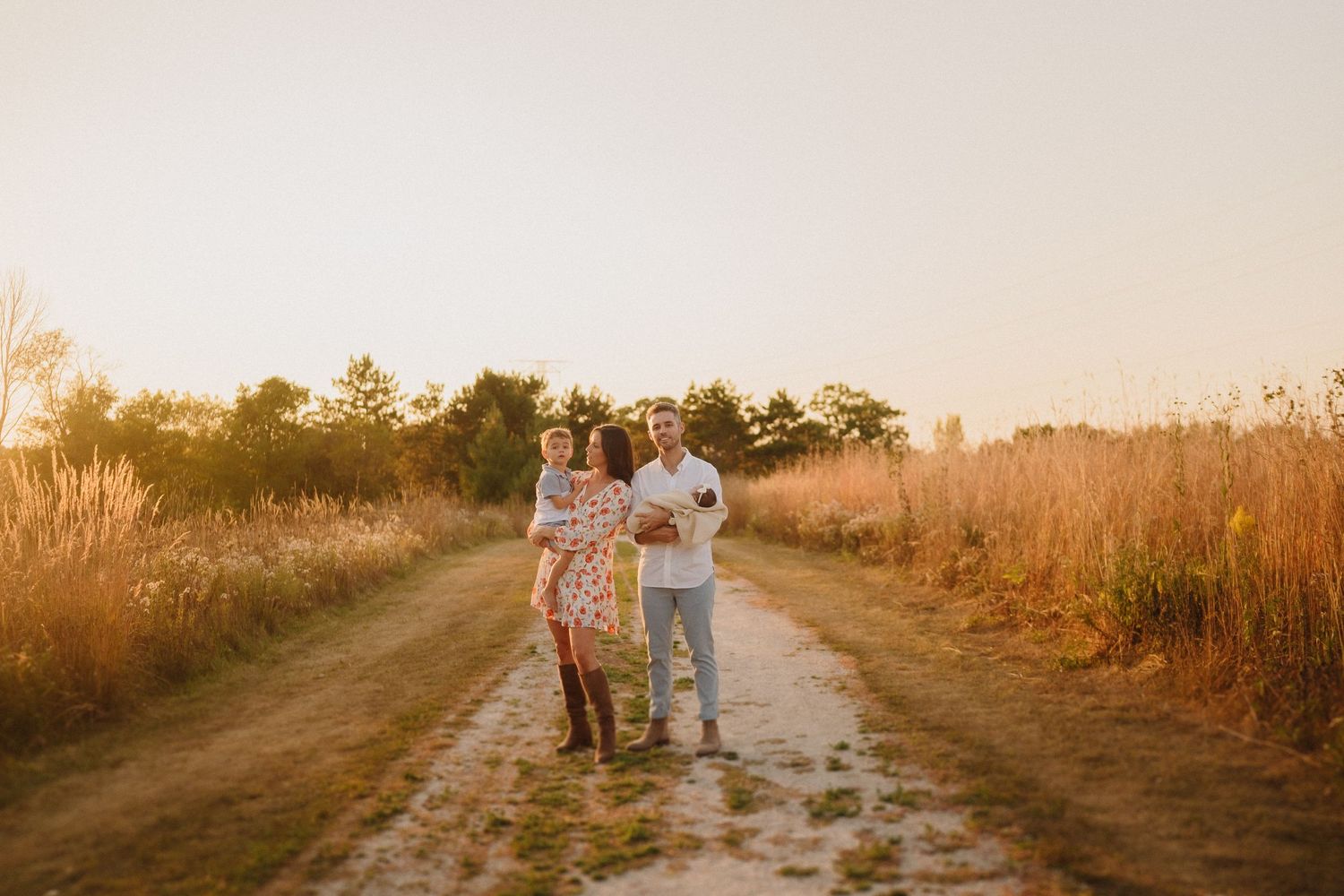 Family walking together on a scenic dirt path during sunset.