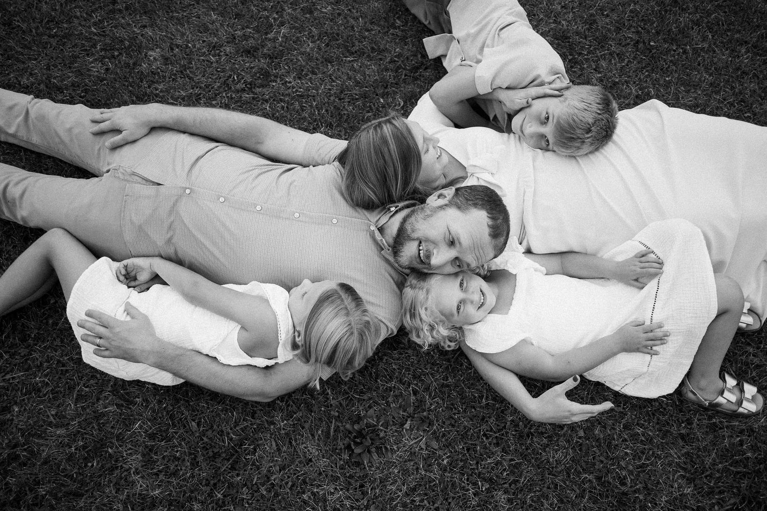 Black and white photo of people lying down in grass.