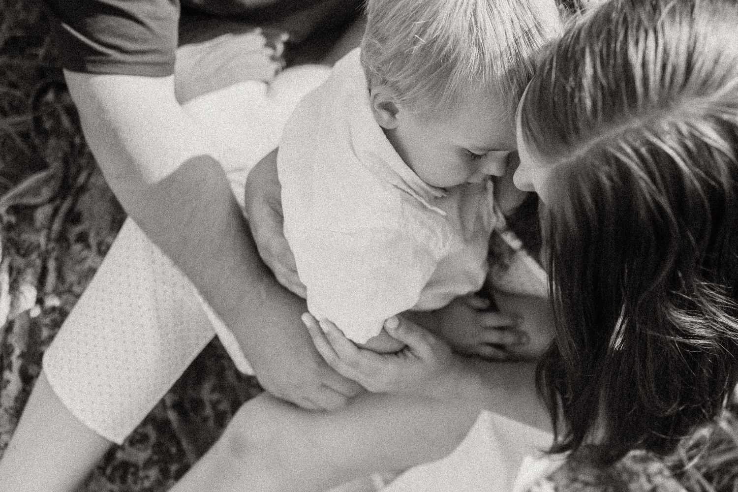 A tender black and white family moment captured while embracing a small child.