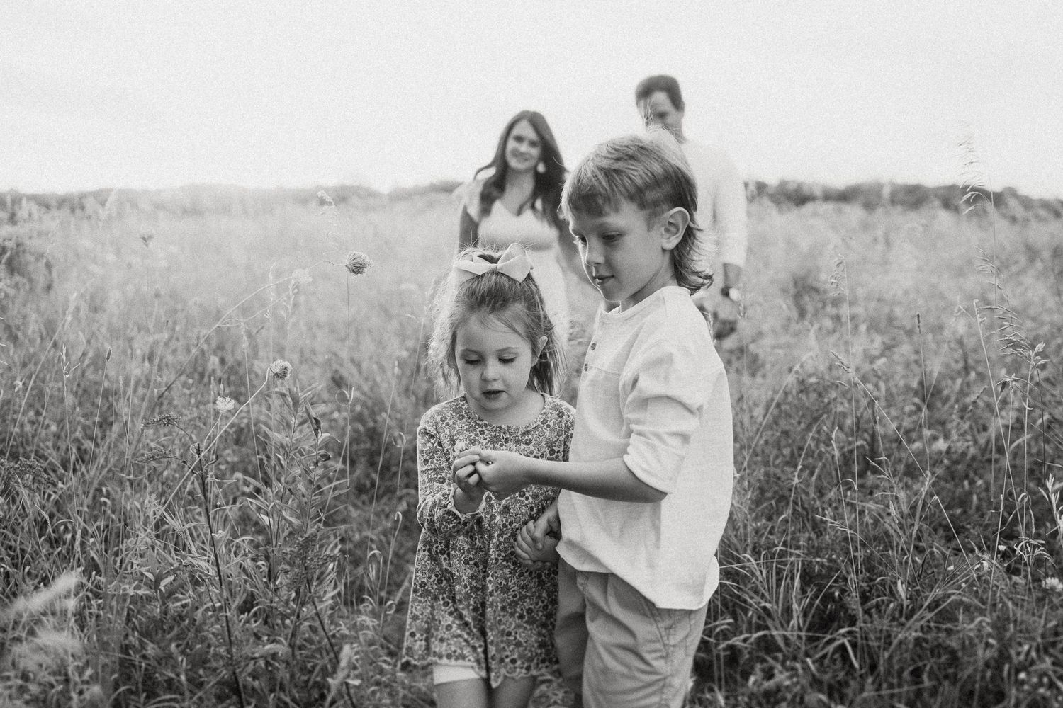 Family walks through a field together in black and white photography.