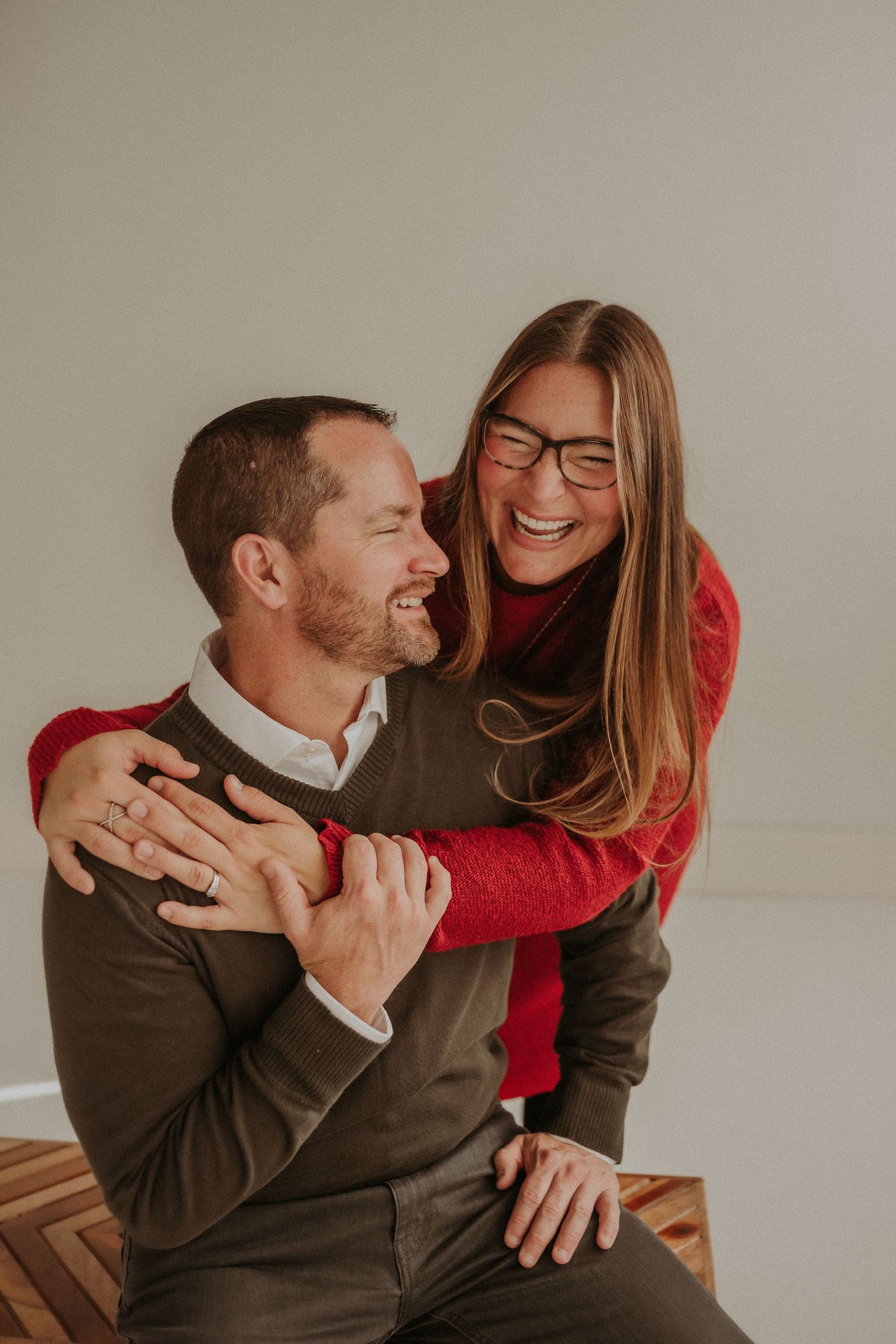 A candid moment of affection between two people wearing red and brown sweaters.