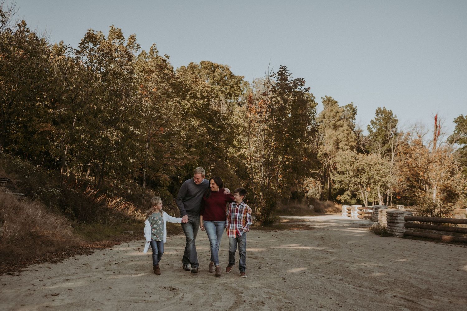 Family walking together on a path through autumn woods during golden hour.