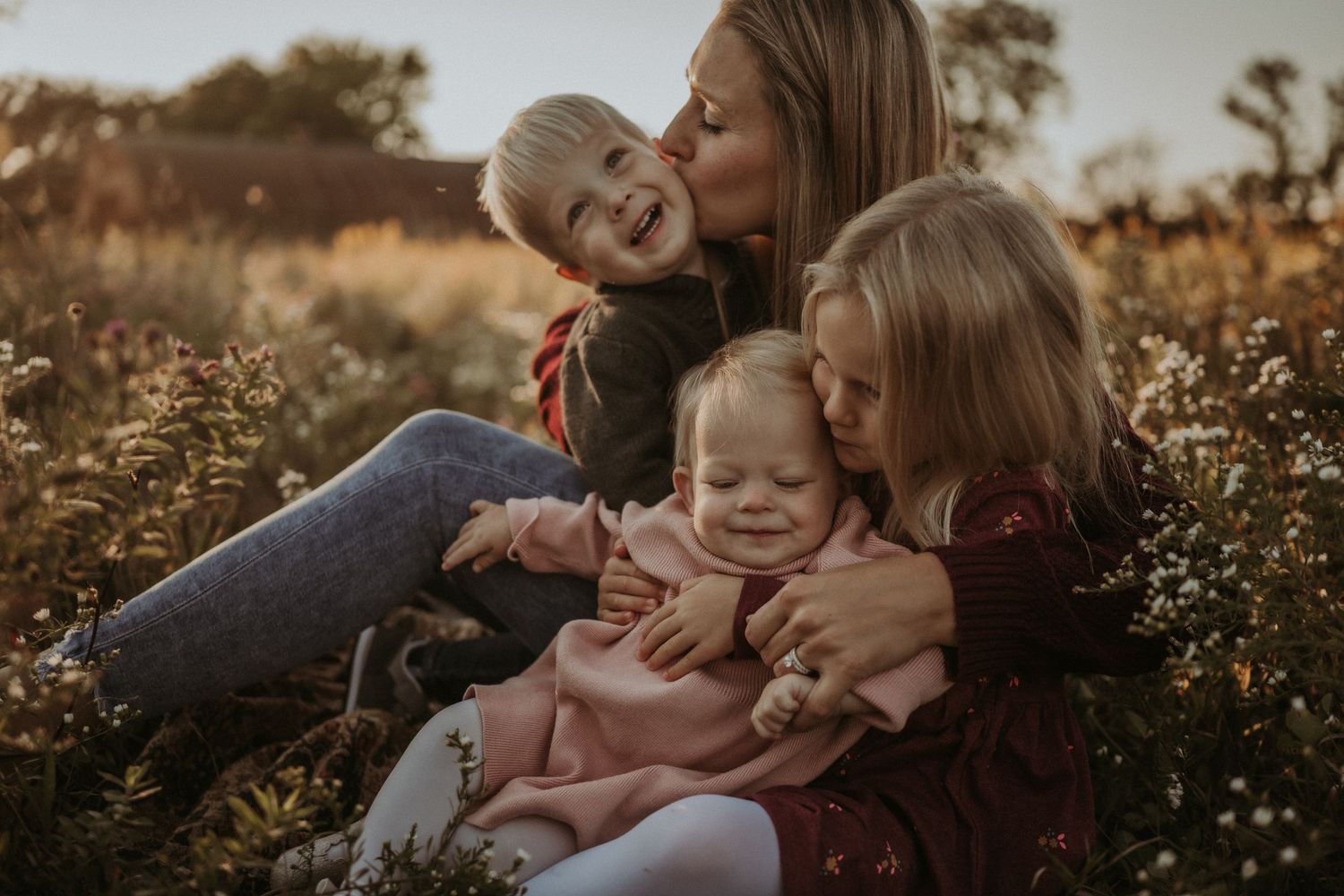 Tender family moment shared in a wildflower meadow during golden hour.