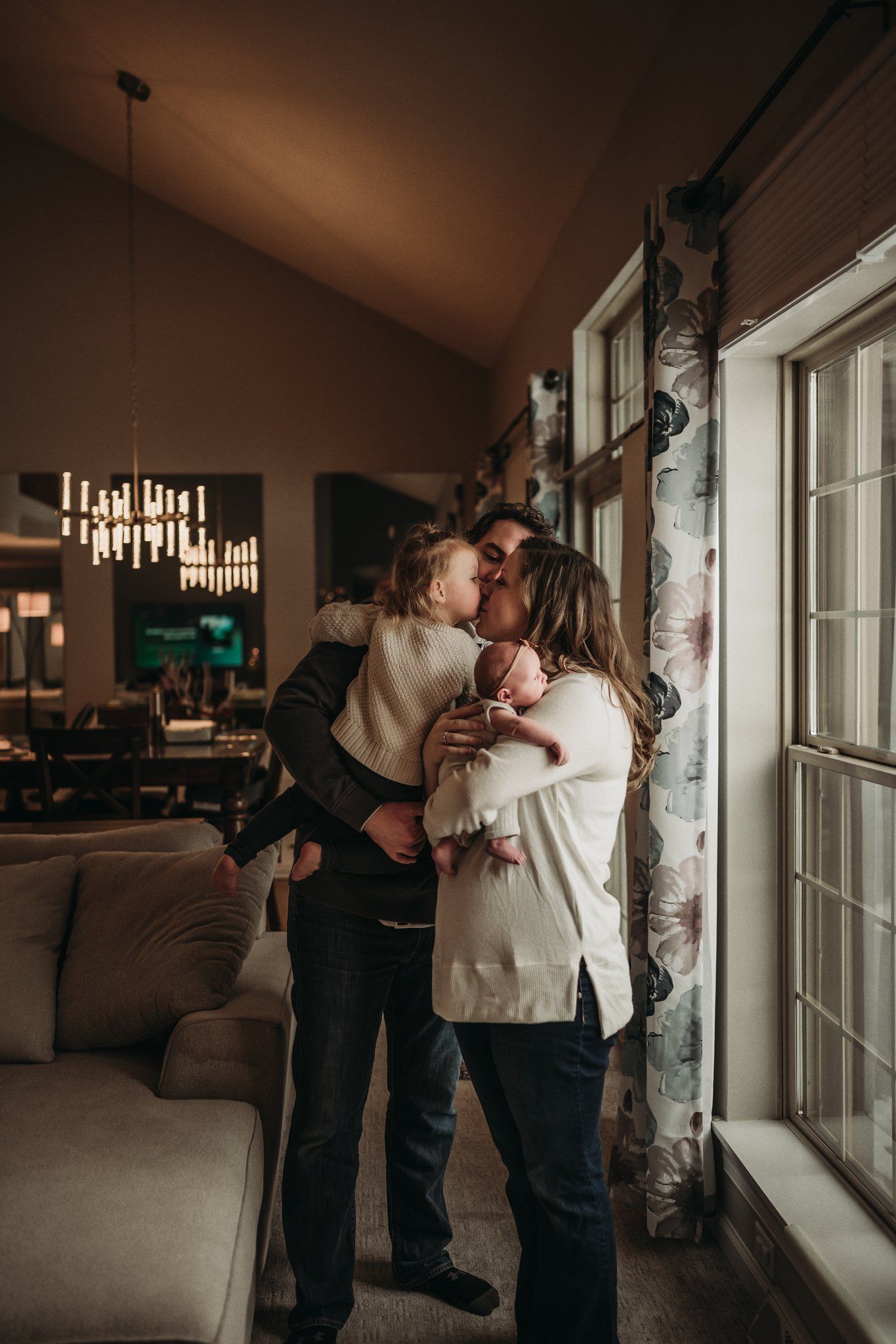 Family sharing tender moment together by large window in living room.