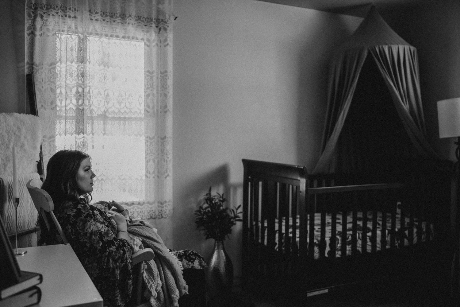Black and white nursery interior with crib and lace curtains visible.