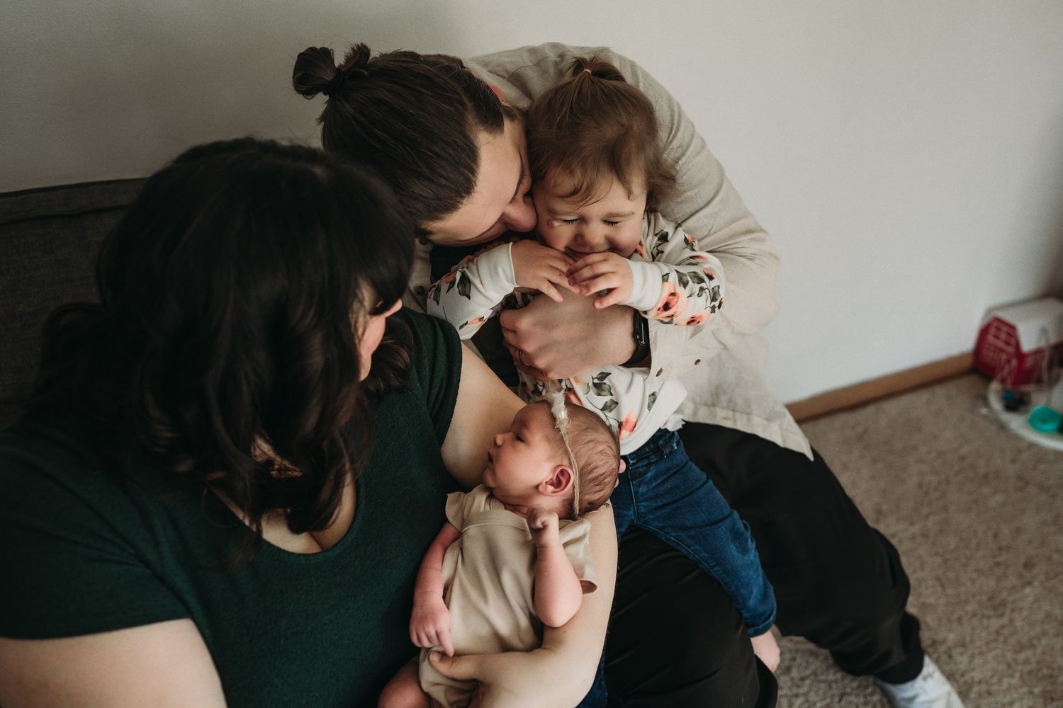Candid family photo capturing playful interaction and laughter on a couch.