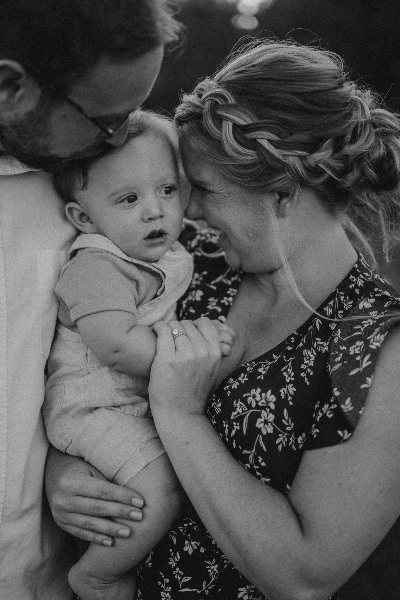 A tender family moment in black and white as parents embrace their baby.
