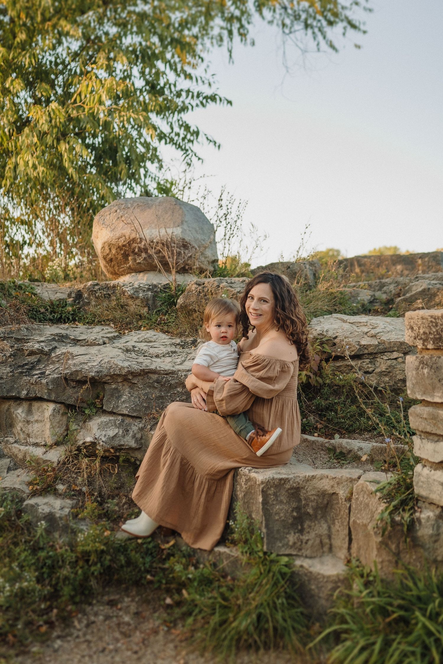 Two figures share a loving embrace while seated on rustic stone steps during golden hour.