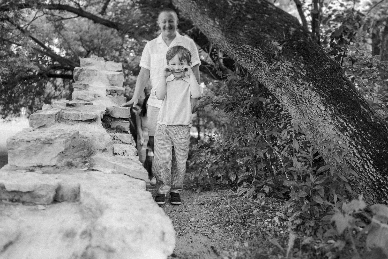 A black and white photo shows figures walking along stone steps near a large tree.