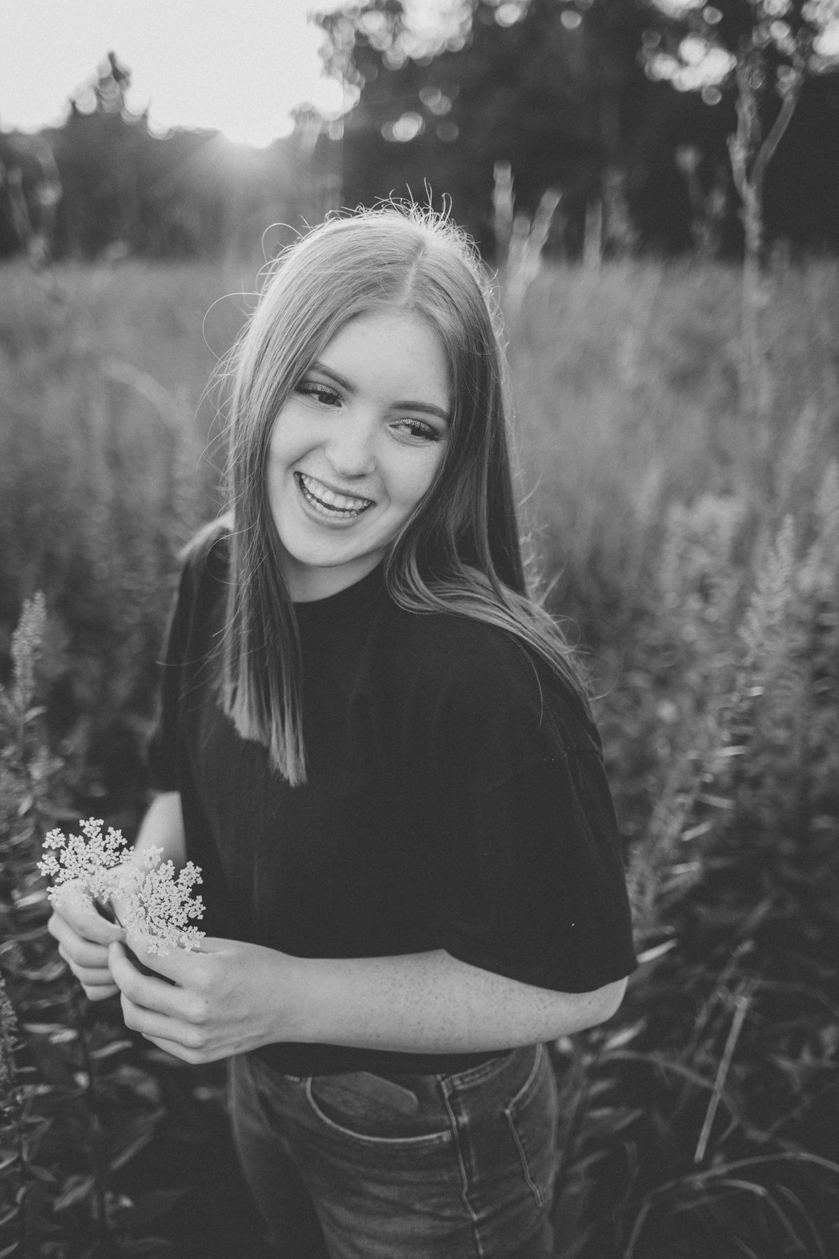 Black and white portrait with wildflowers in tall grass.