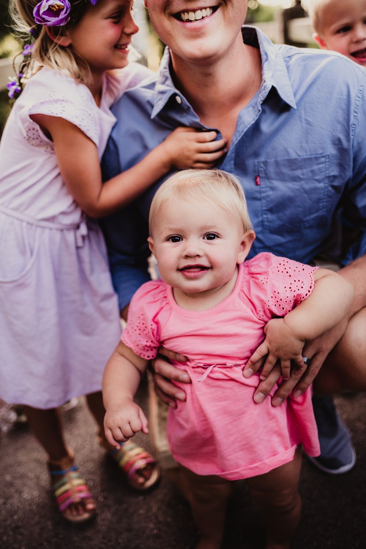 A close-up family portrait showing joyful expressions and pink floral clothing.