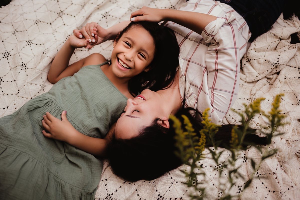 Two people laying on blanket outdoors sharing genuine laughter together.