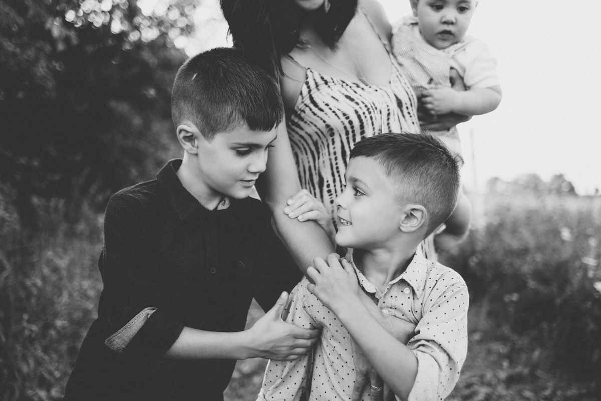 Black and white photo of children interacting playfully in natural outdoor setting.