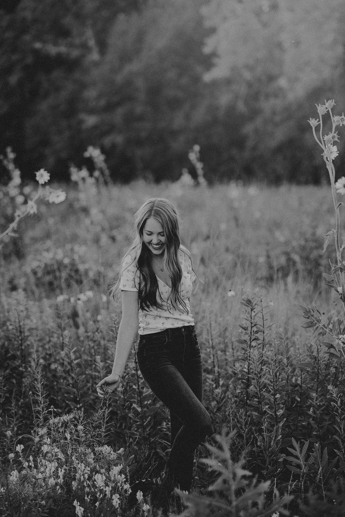 Black and white candid portrait in a meadow with wild summer flowers.