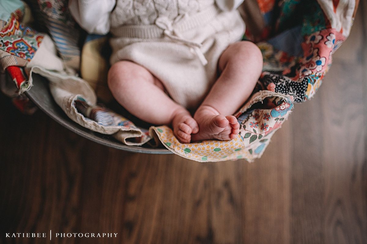 Close-up of tiny baby feet resting on a floral patterned fabric.