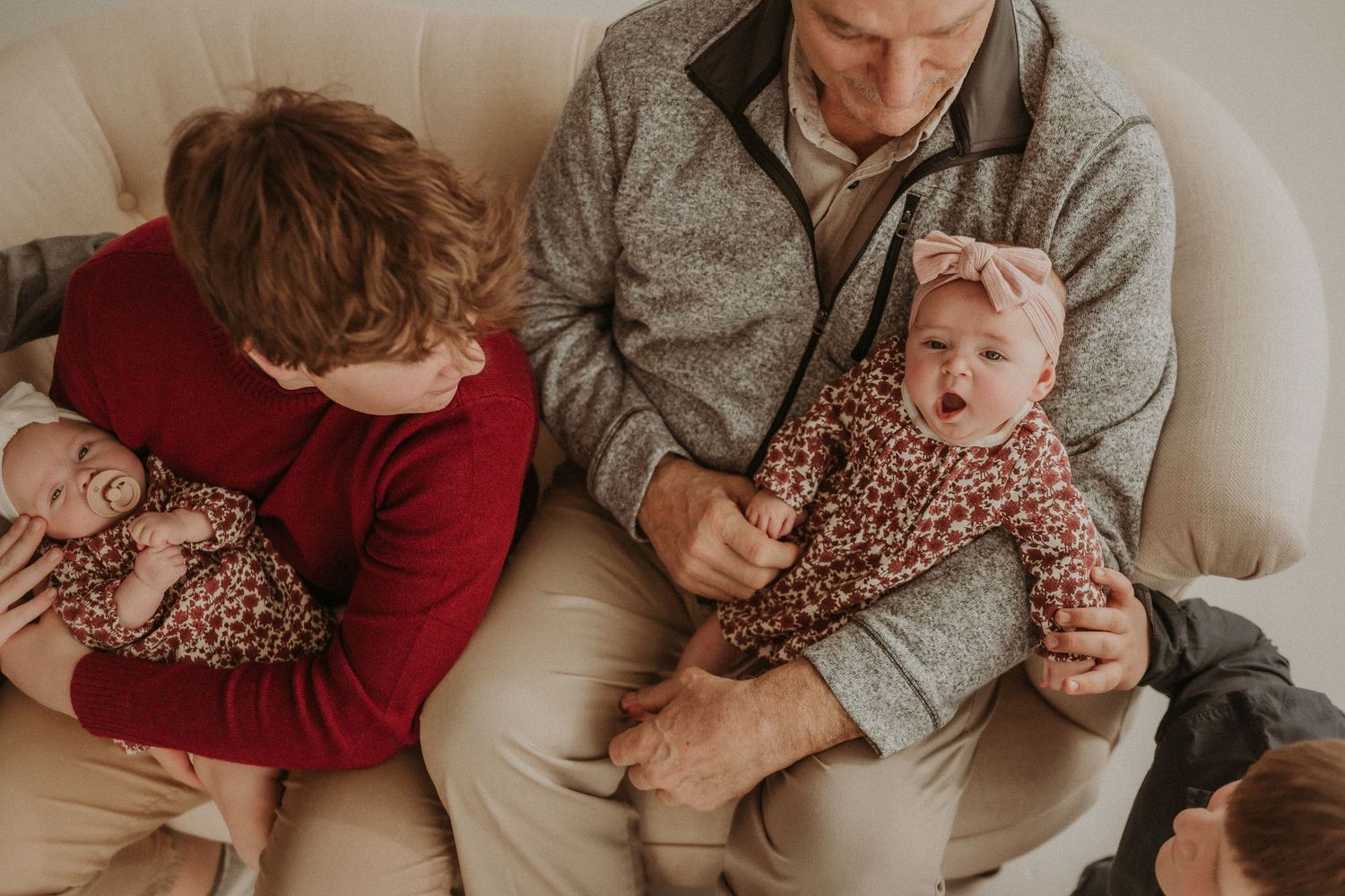 Close up view of family members sitting together on beige couch.