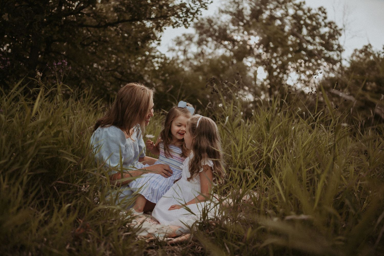 A heartwarming moment shared between family members sitting in tall grass at sunset.