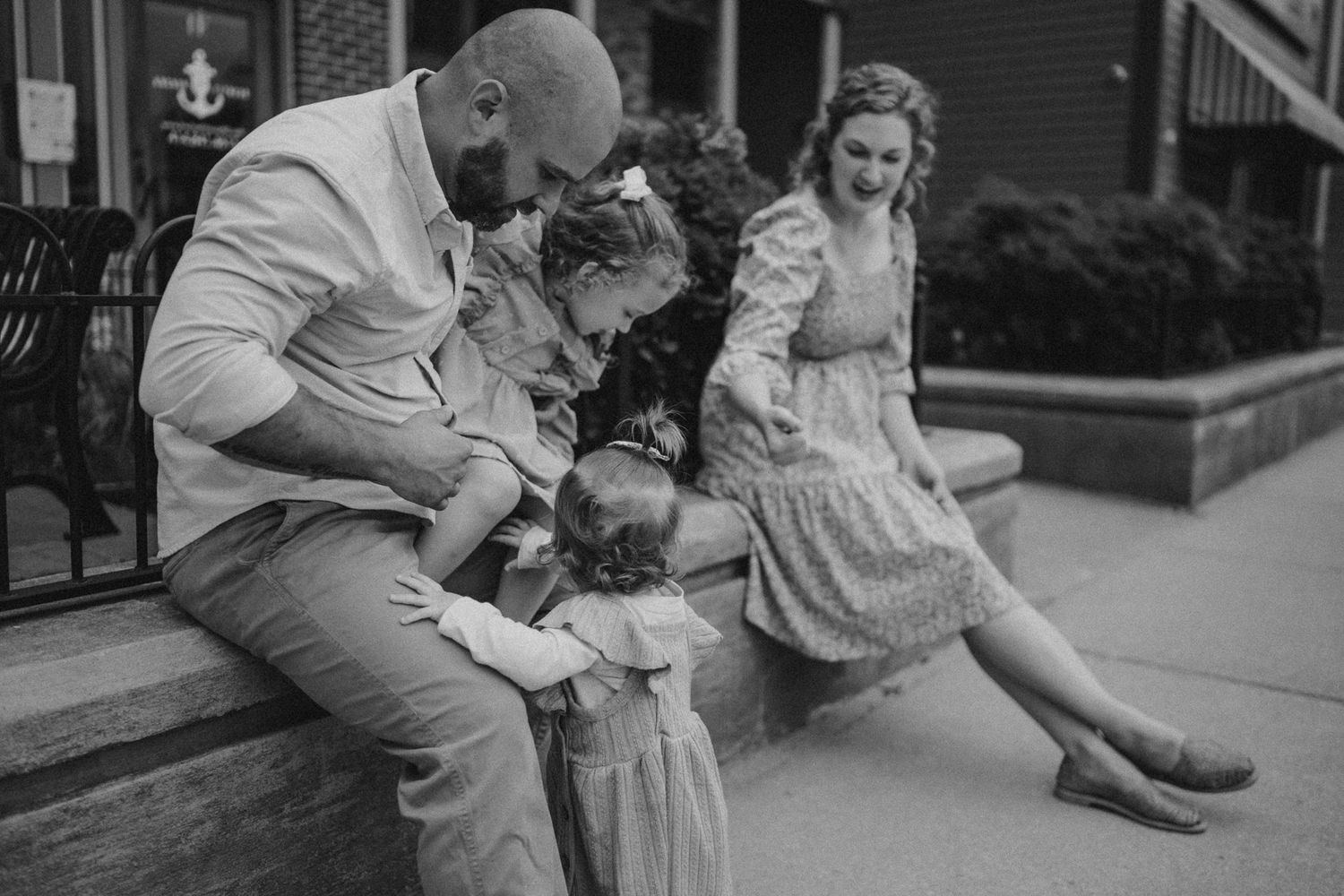 A black and white capture of a family sharing an intimate moment on city steps.