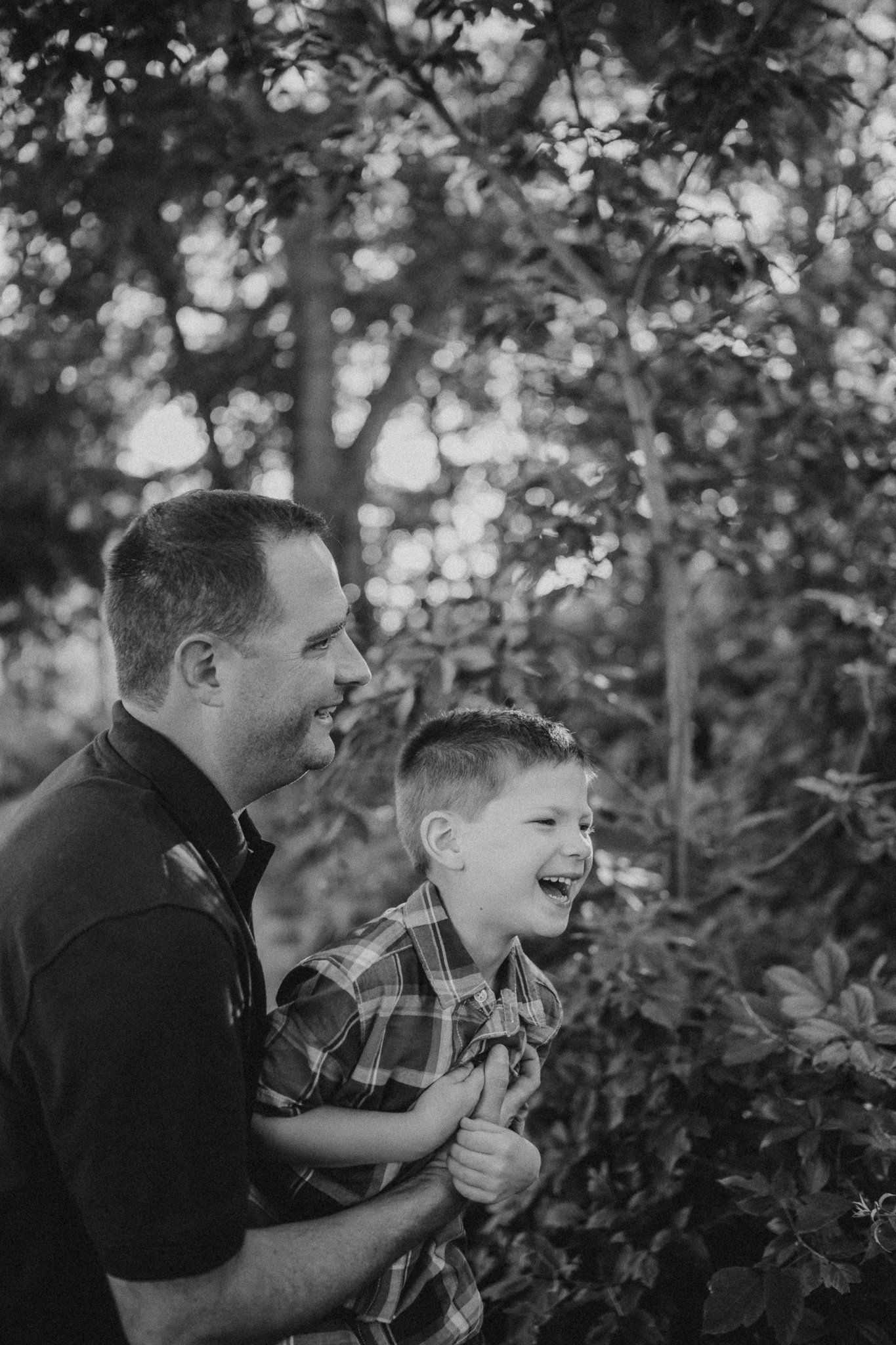 Black and white candid shot capturing laughter and joy between parent and child.