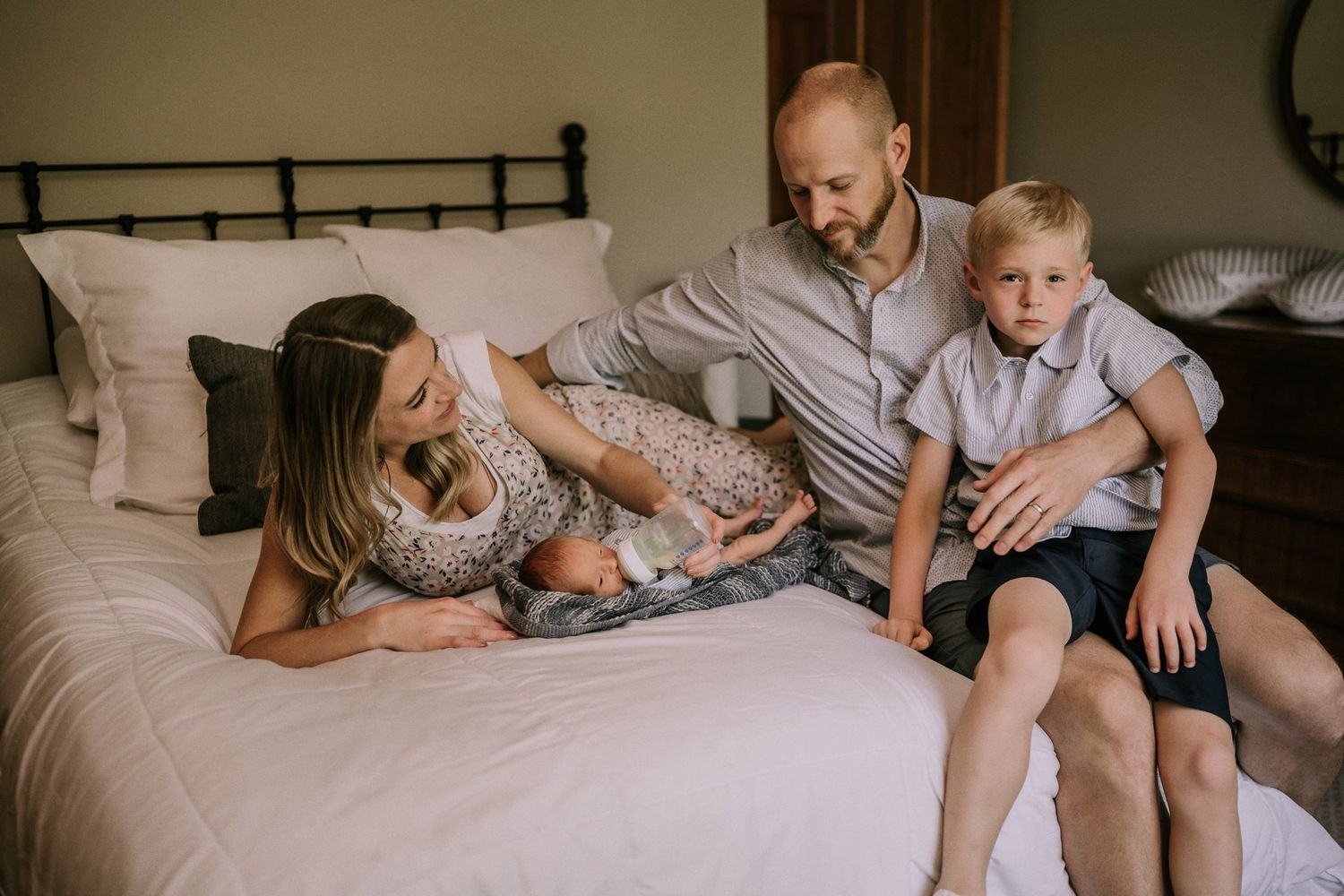 A family enjoying quality time together on a cozy bed with their newborn.