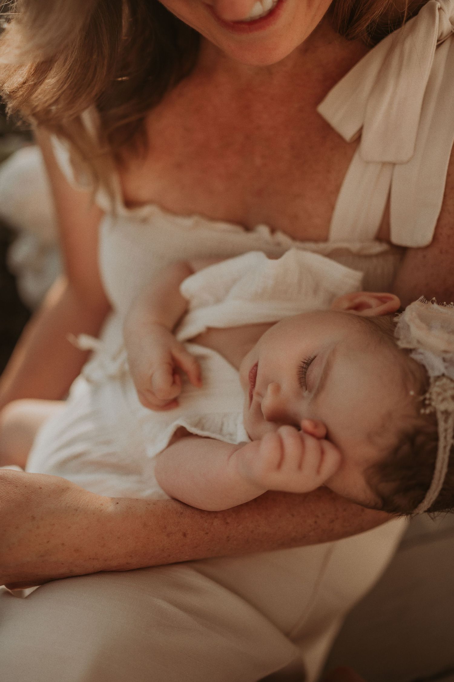 Soft close-up capture of a peaceful sleeping baby in white clothing.