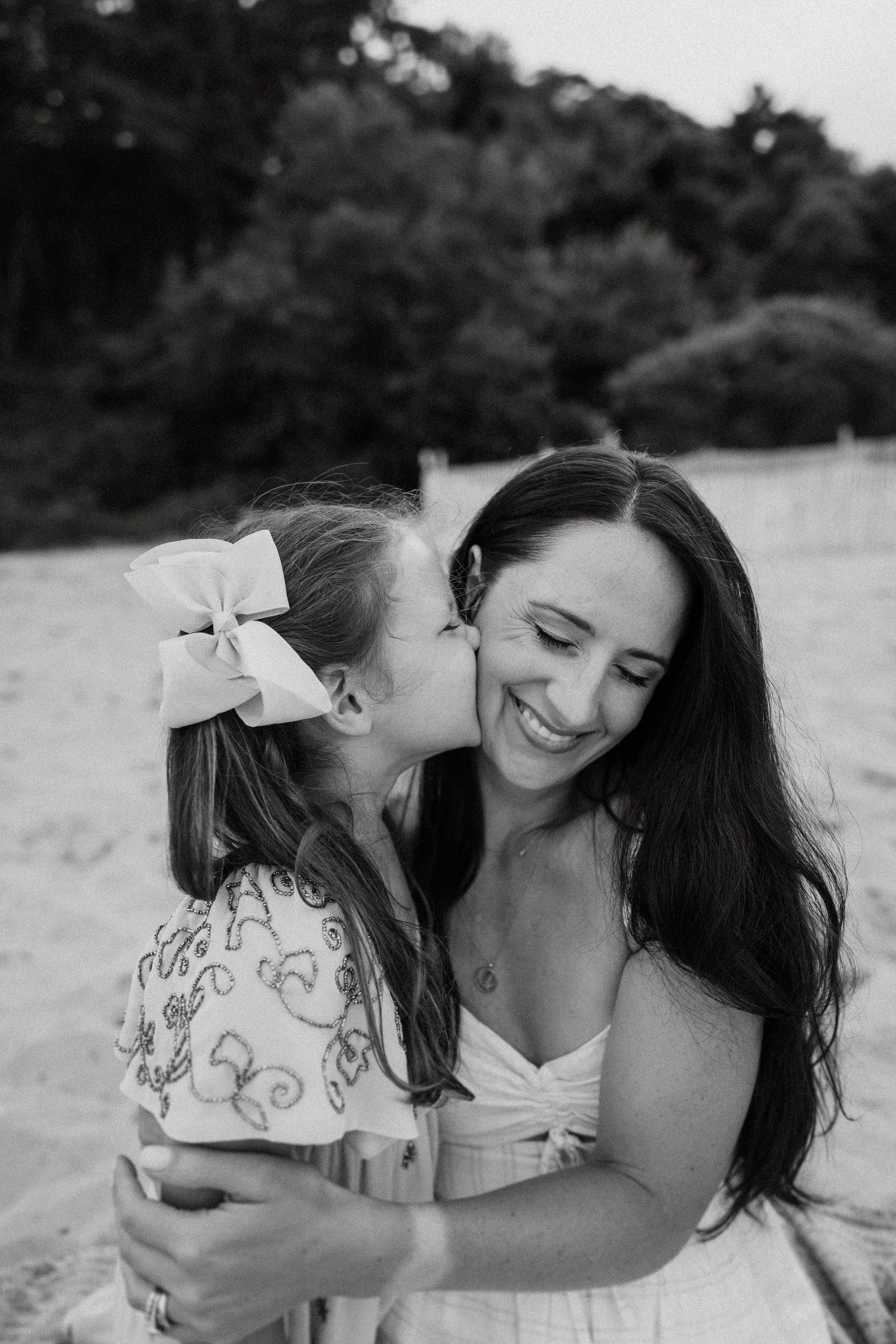 A sweet black and white portrait of two people sharing an affectionate moment outdoors.