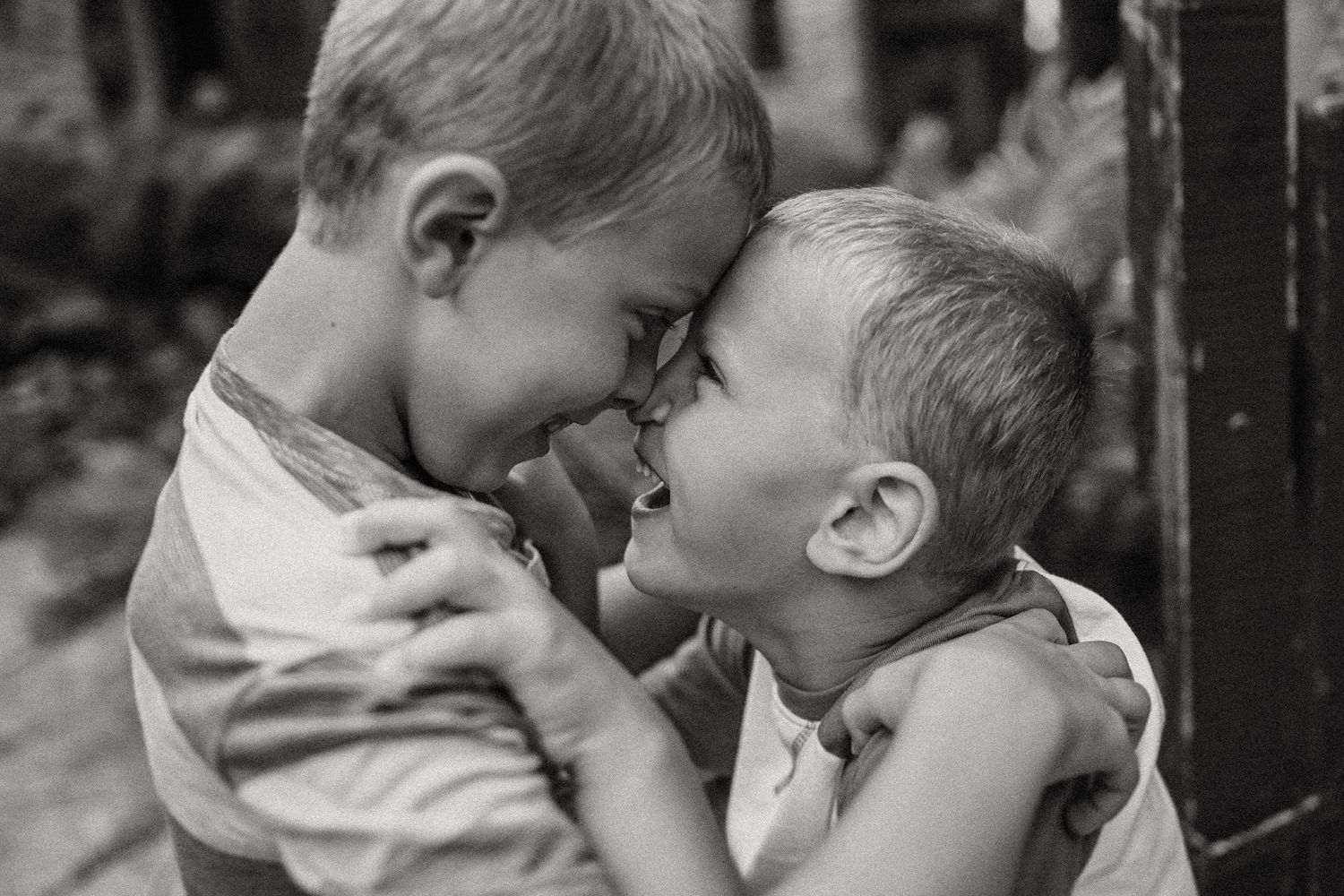 Two young children sharing a joyful laugh together in black and white.