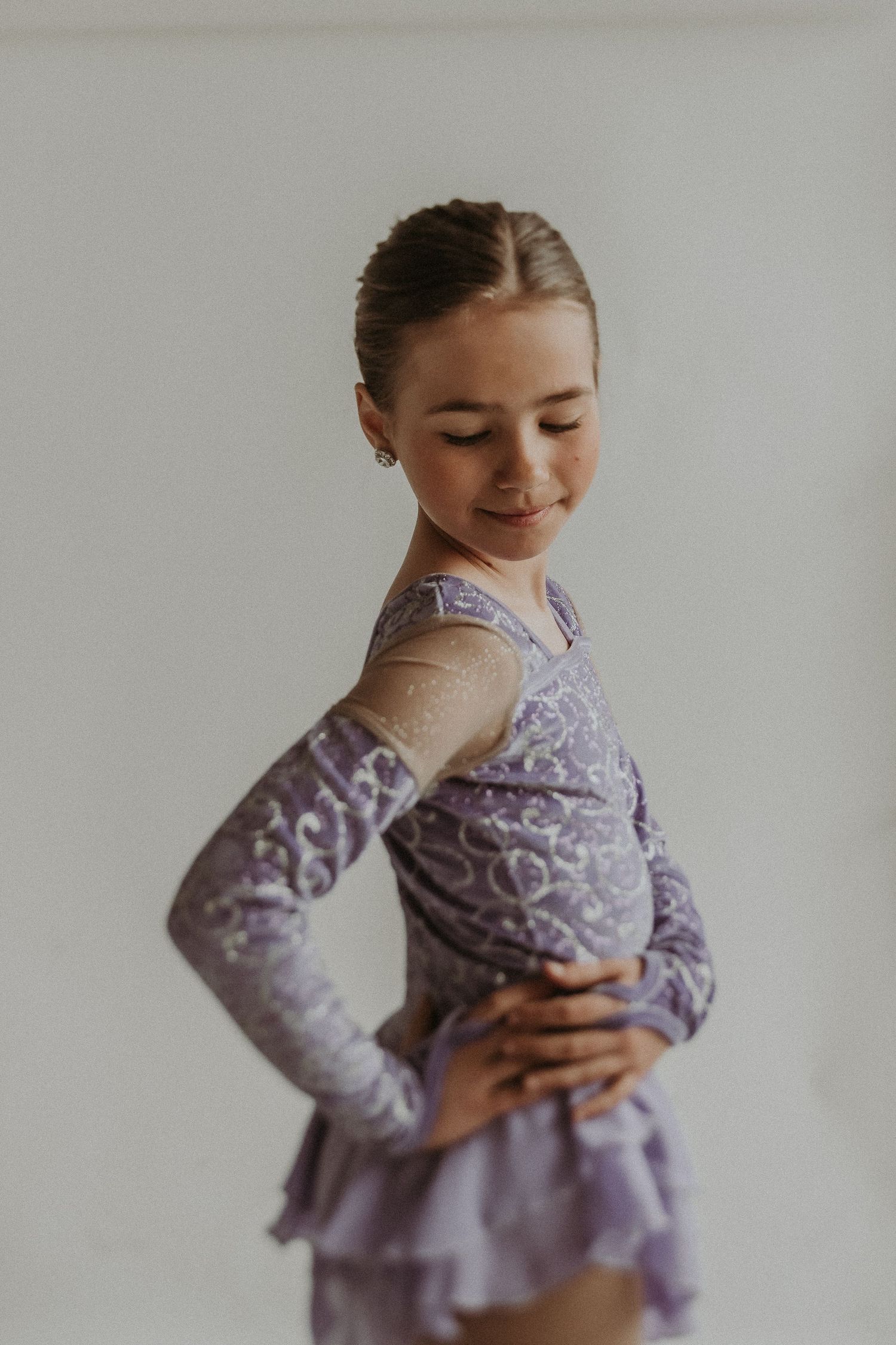 Side view of figure skater in purple costume with delicate mesh detailing and tiered skirt.