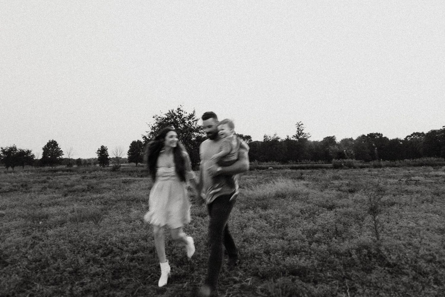 Black and white image of a family in motion across a grassy field.