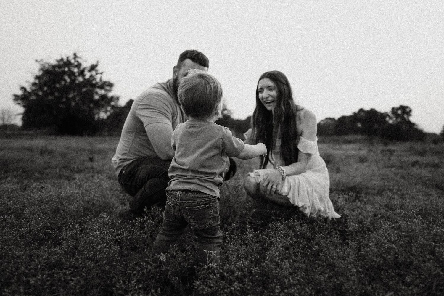 Black and white capture of a family interaction in an open field.