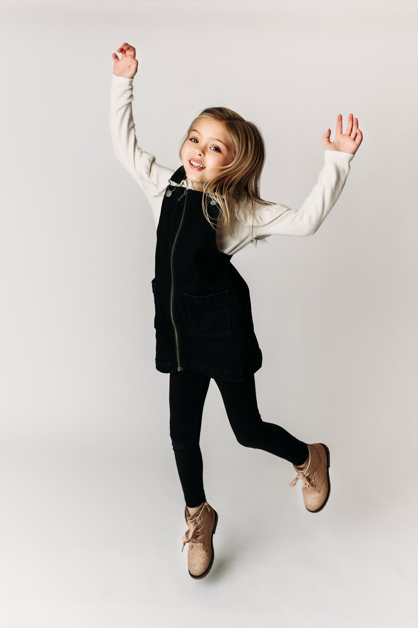 Energetic jump pose in black and white outfit against studio background.