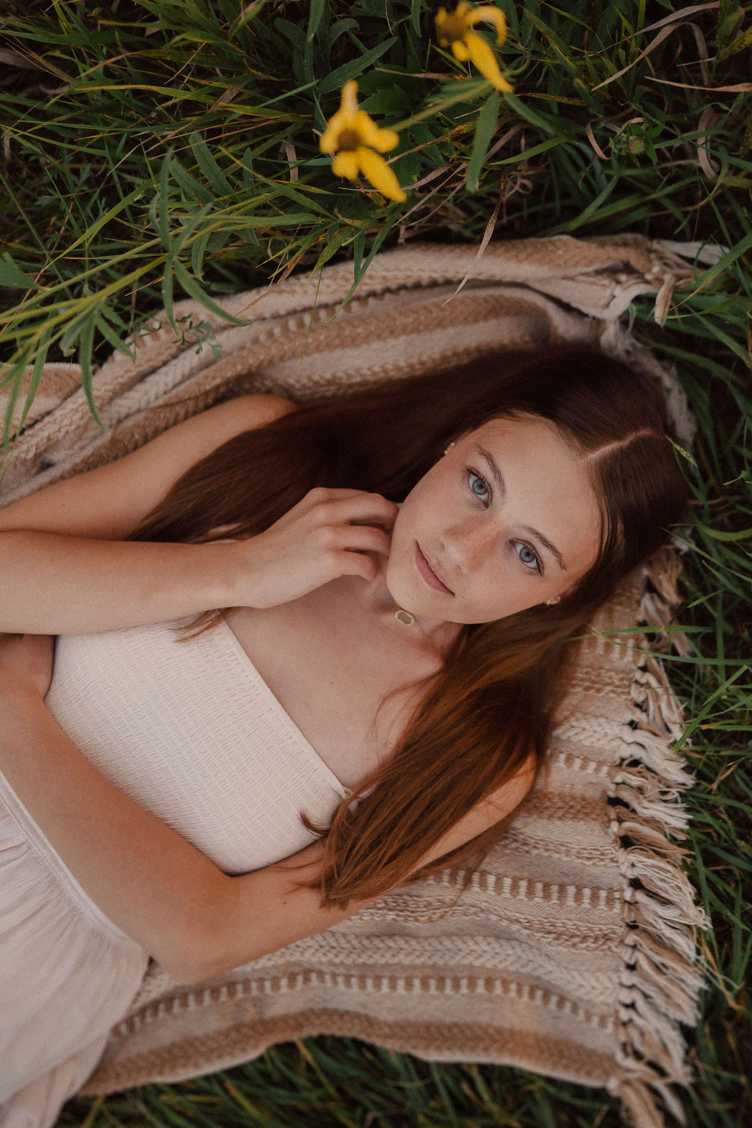 A relaxed portrait on a textured blanket surrounded by yellow flowers and grass.