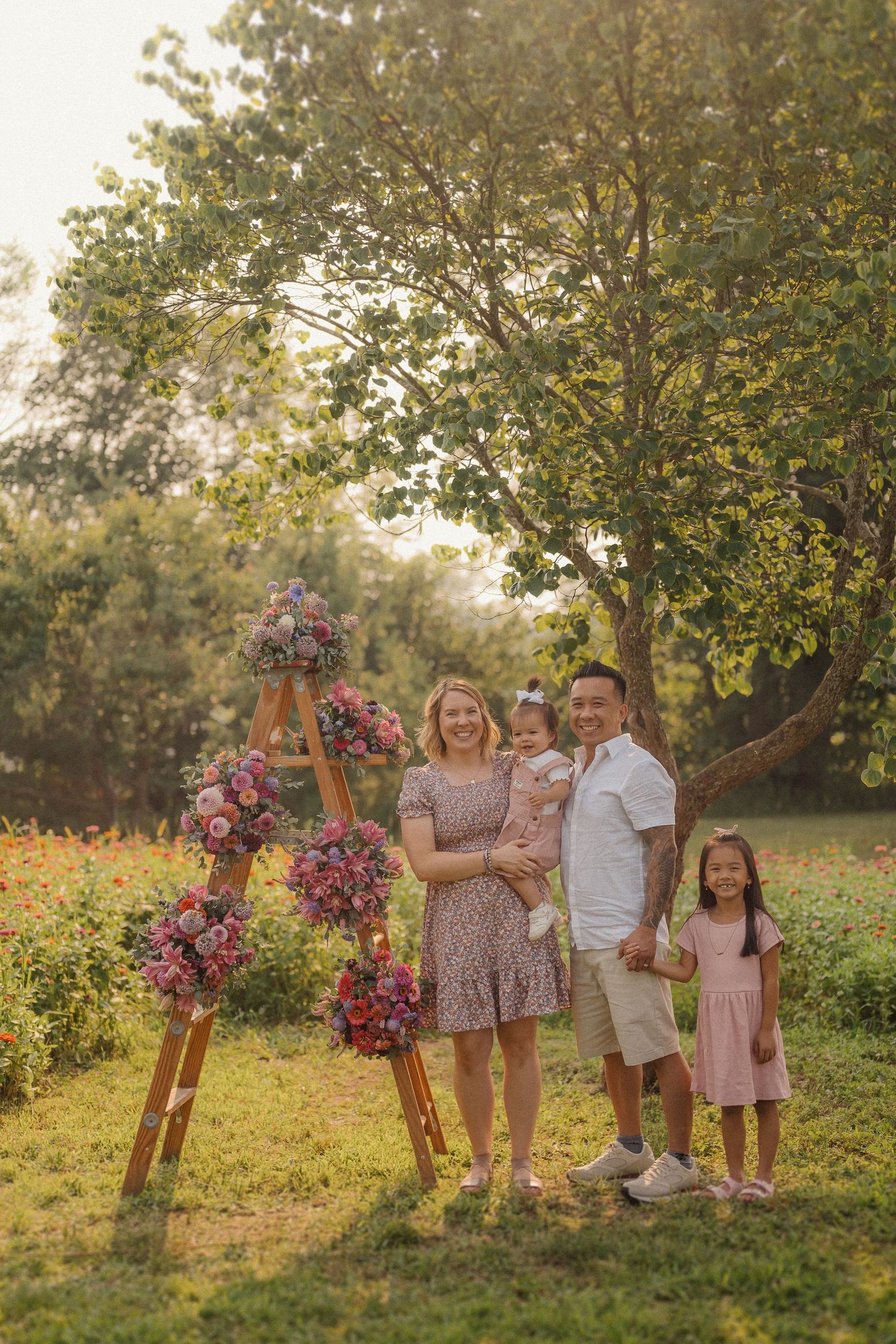 Family gathering outdoors near wooden stands adorned with colorful floral arrangements.