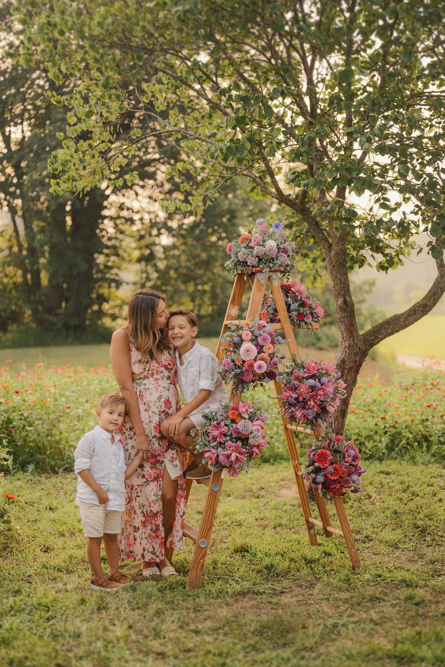 Wooden ladder display with lush pink floral arrangements against a green garden backdrop.