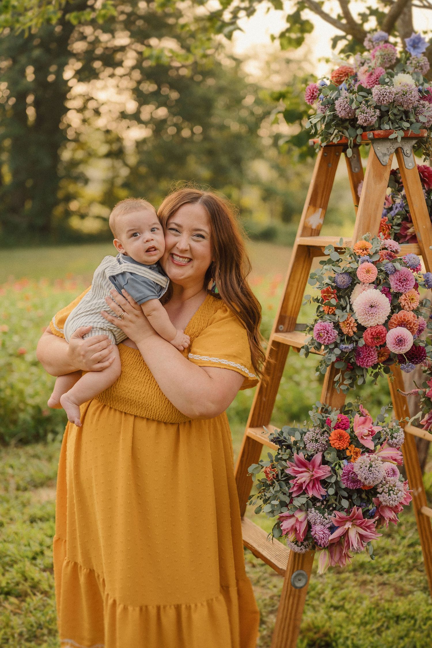 Family portraits at sunset with vibrant floral arrangements and yellow dress against natural outdoor backdrop.