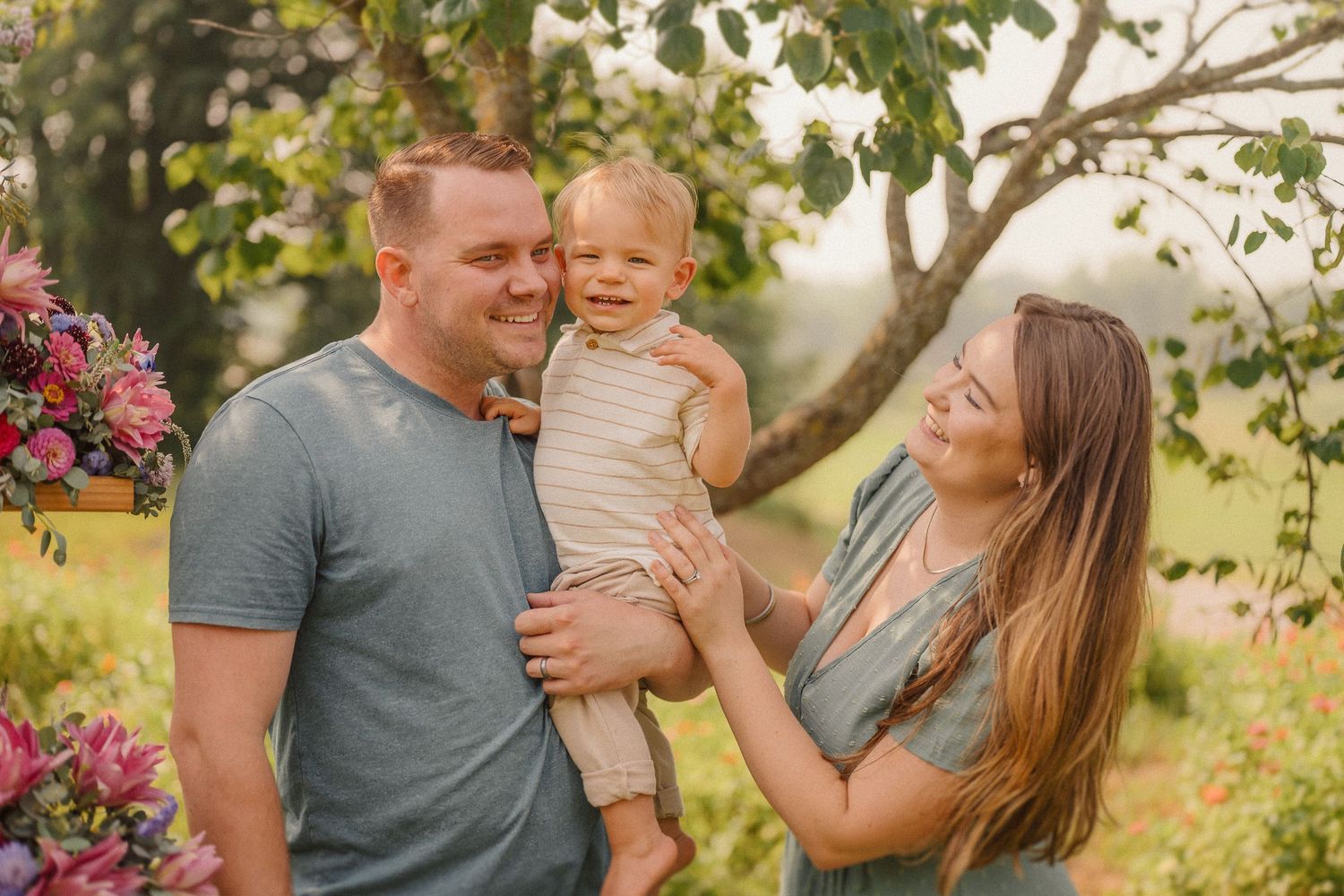 Sweet candid moments shared between family members in a warm outdoor setting with floral decorations.