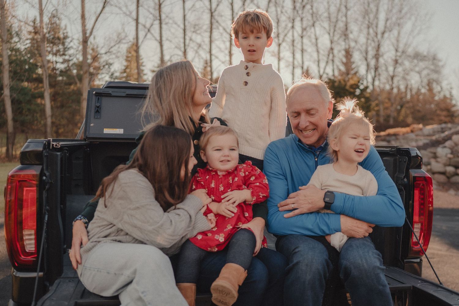 Family gathering in the back of a pickup truck during sunset.