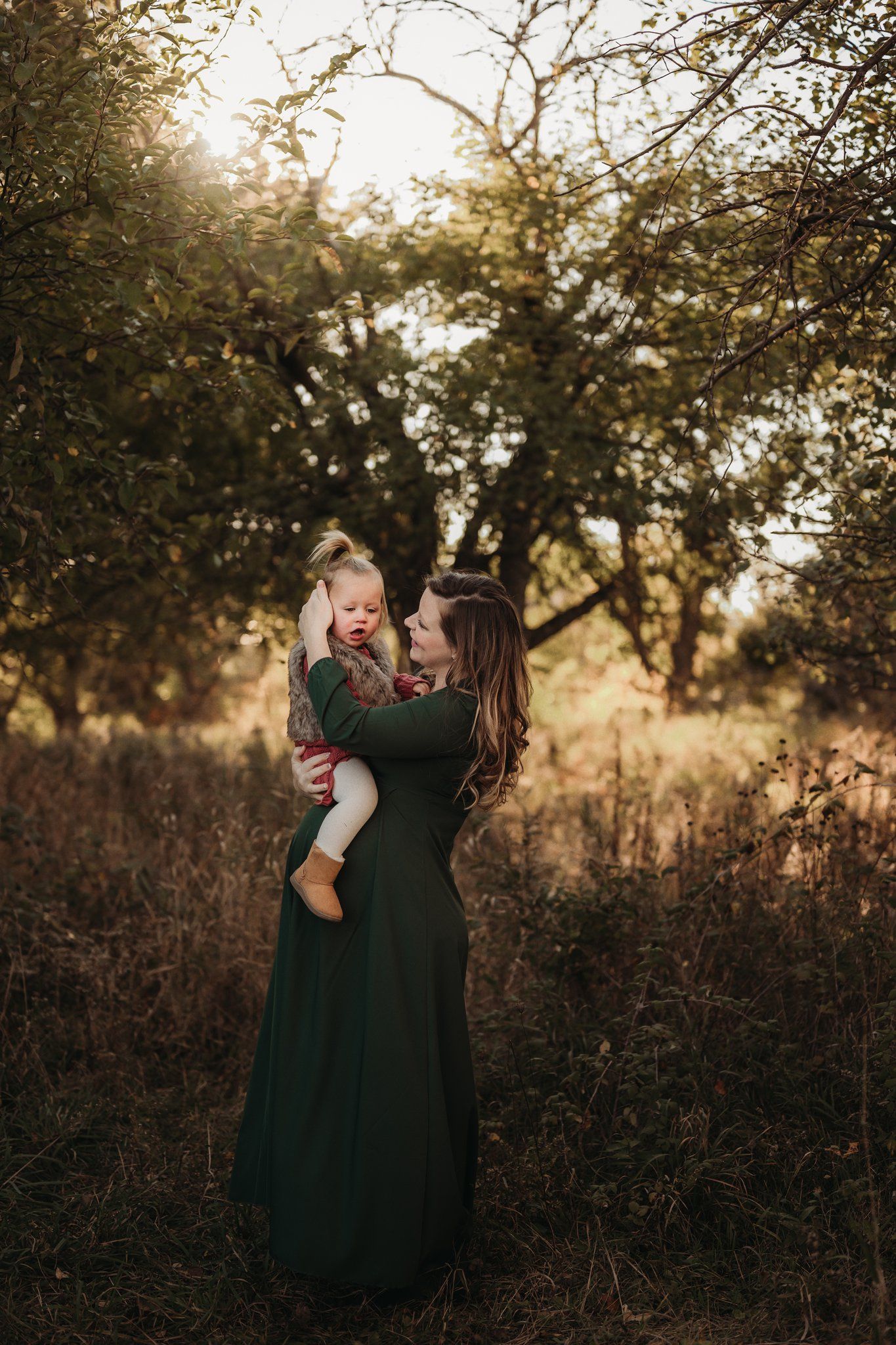 A tender outdoor portrait in a forest setting at golden hour featuring a long green dress.