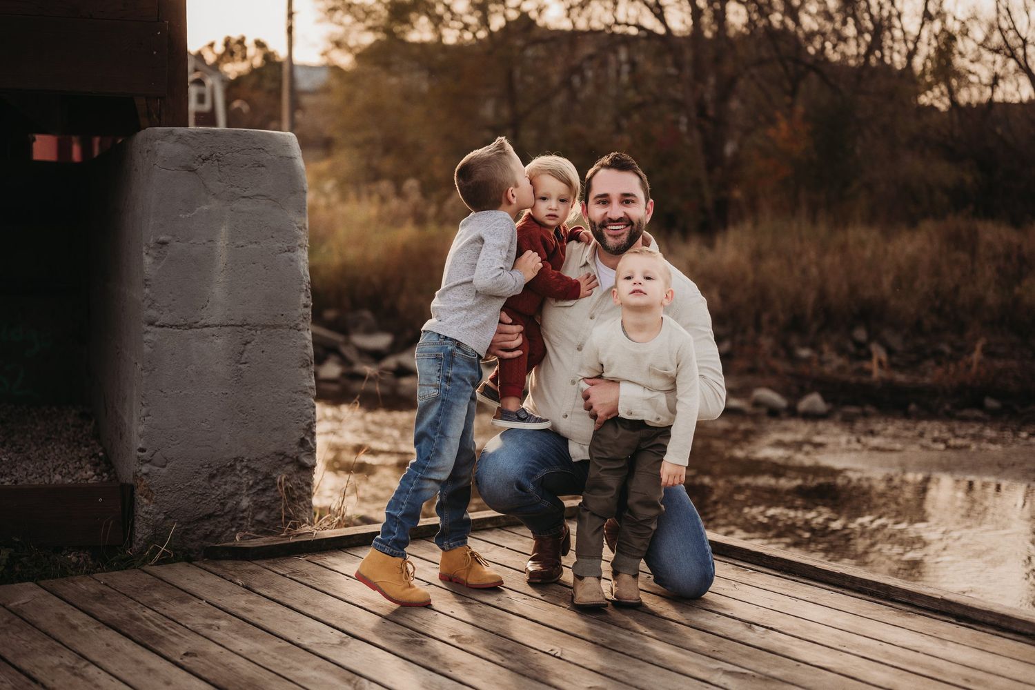 A joyful family moment captured on a wooden deck at sunset with warm autumn colors in the background.
