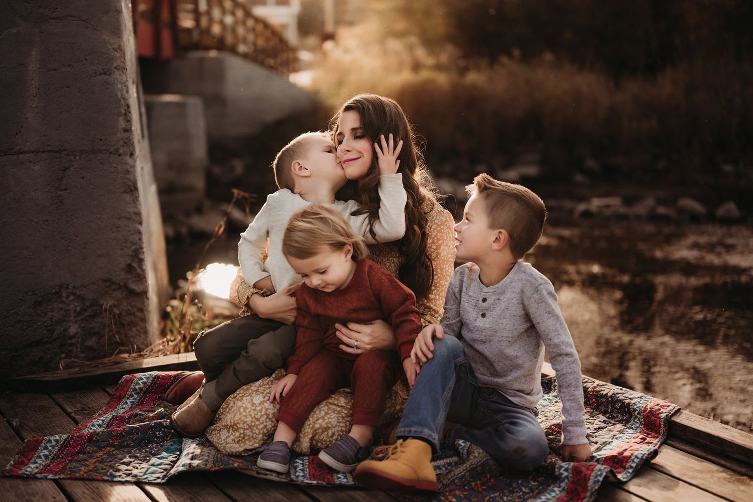 A family shares intimate moments together on a picnic blanket at sunset.