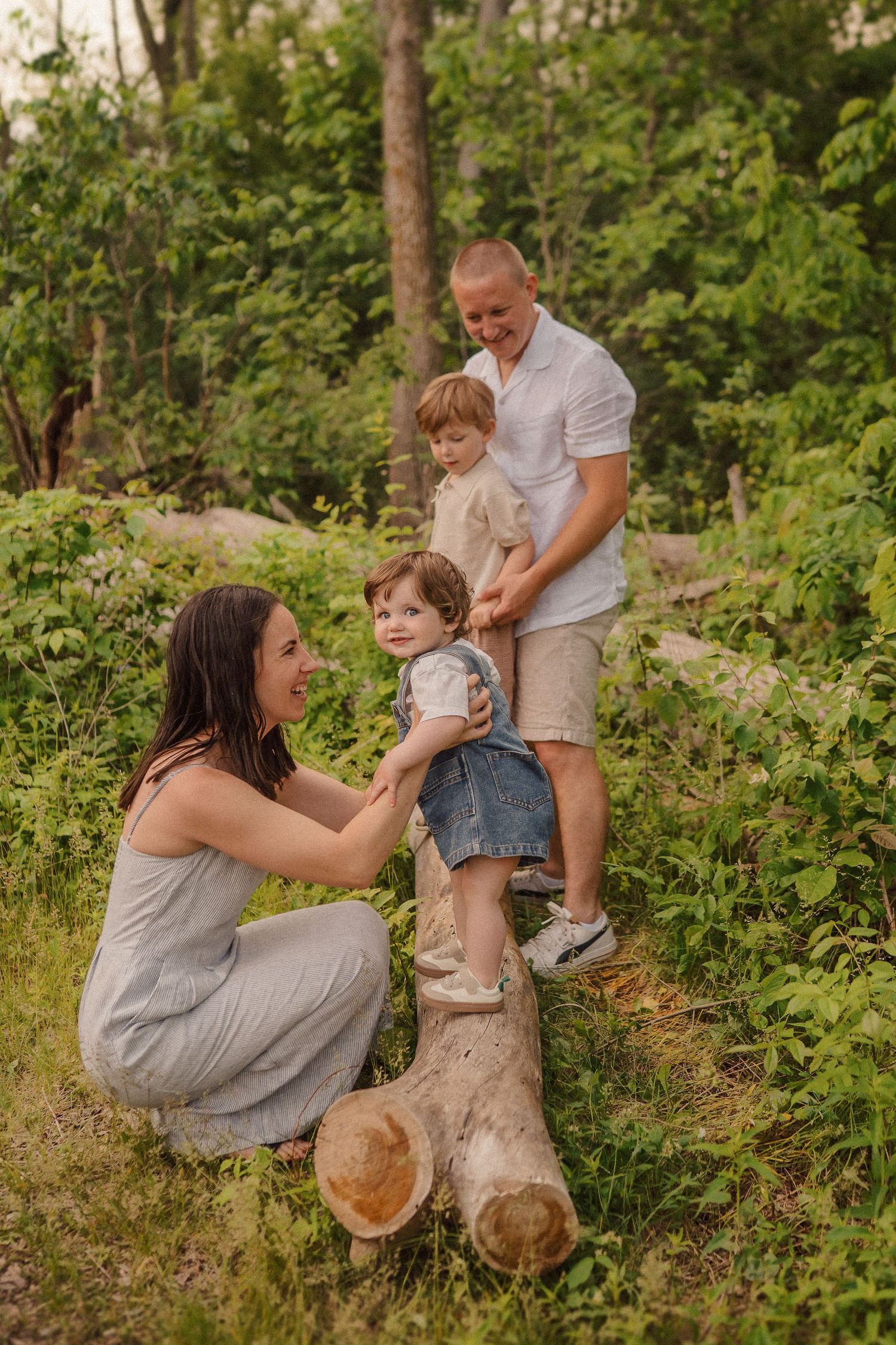 Sweet family interactions while balancing on fallen logs in a wooded setting.