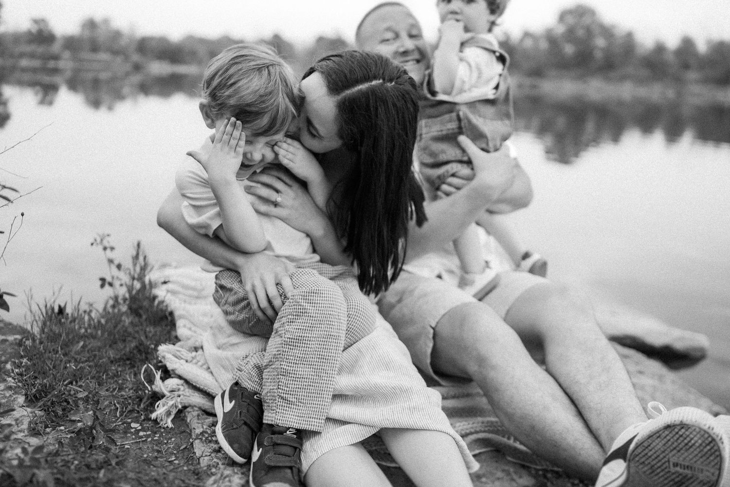 Black and white candid photo showing joyful moments by a tranquil lake.