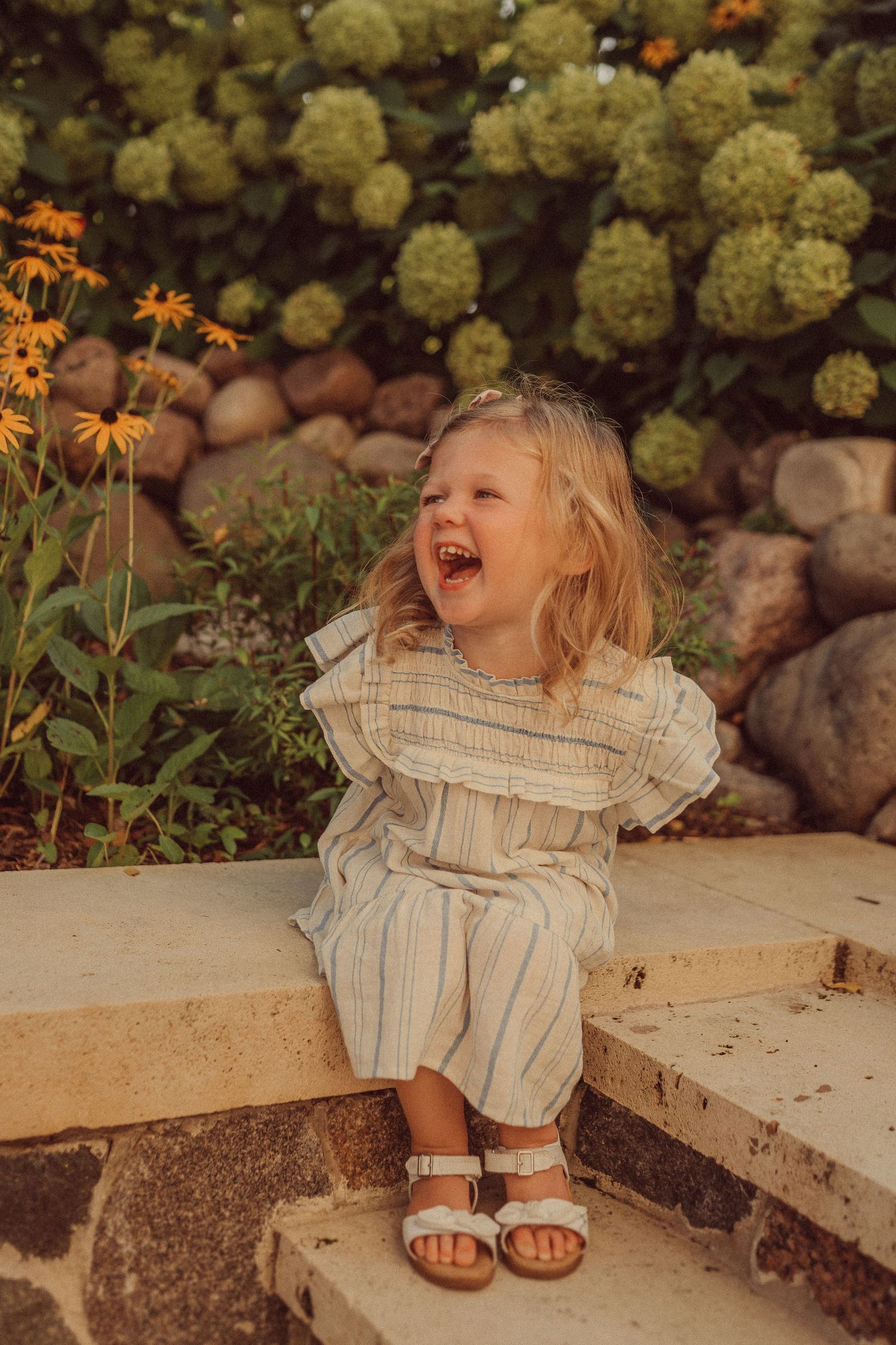 A joyful moment captured on stone steps with blooming hydrangeas and orange flowers in the background.