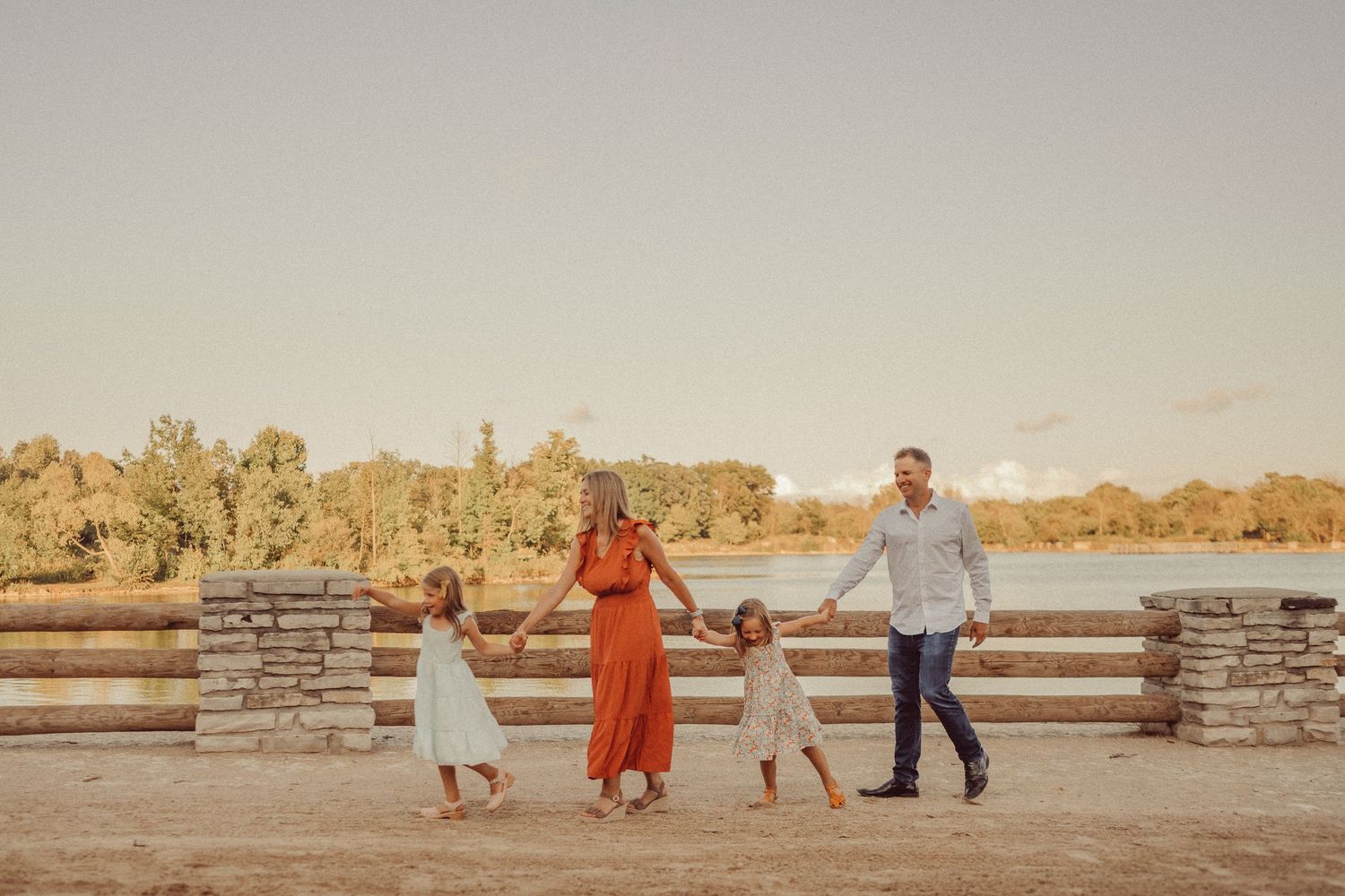 A family enjoying a sunset moment together near a stone wall fence.