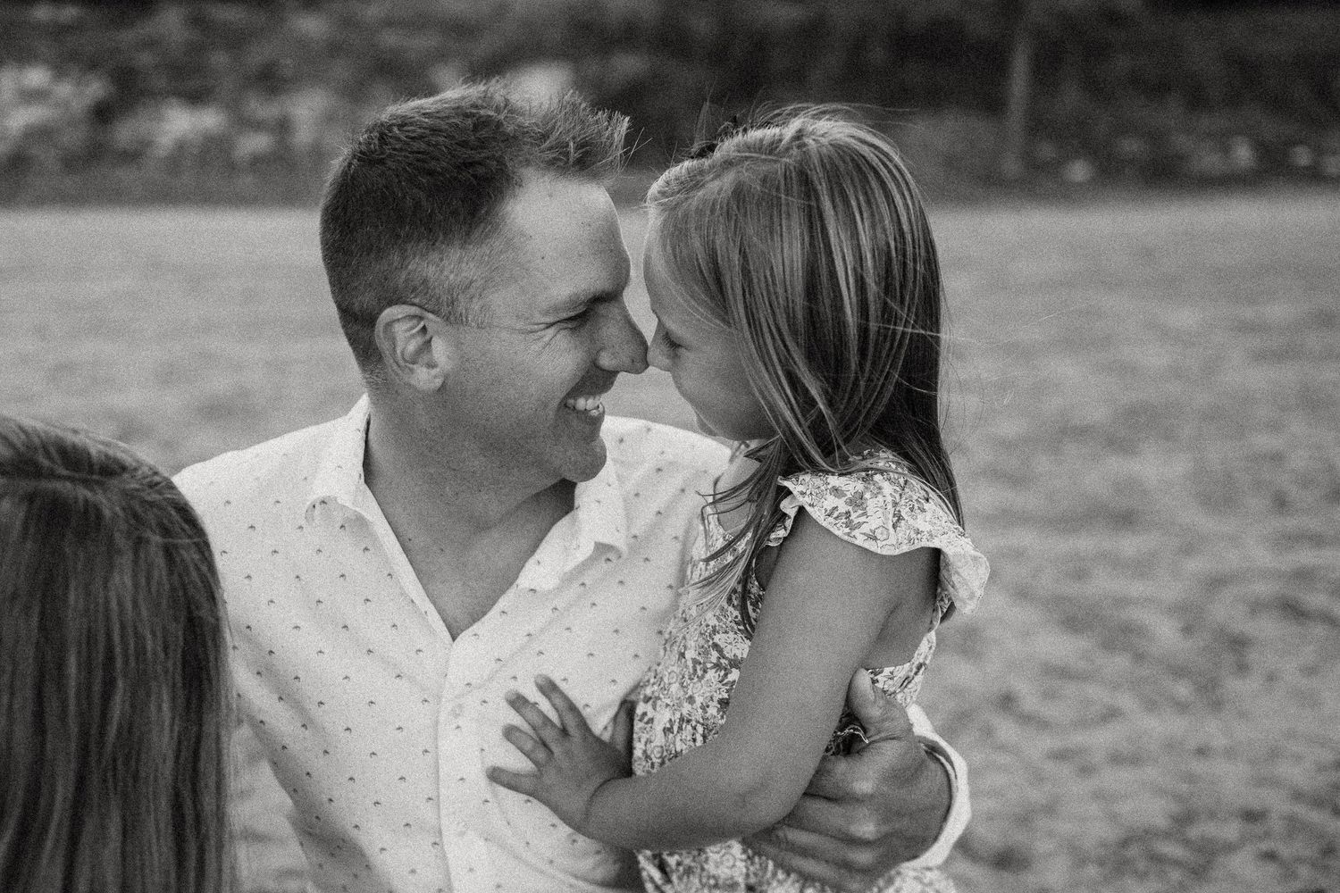A touching black and white moment of laughter and affection shared outdoors in a natural setting.