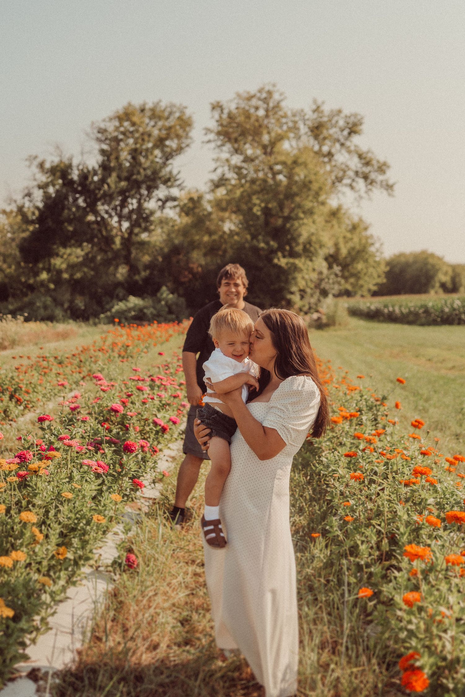 A tender family moment captured in a field of red poppies during sunset.