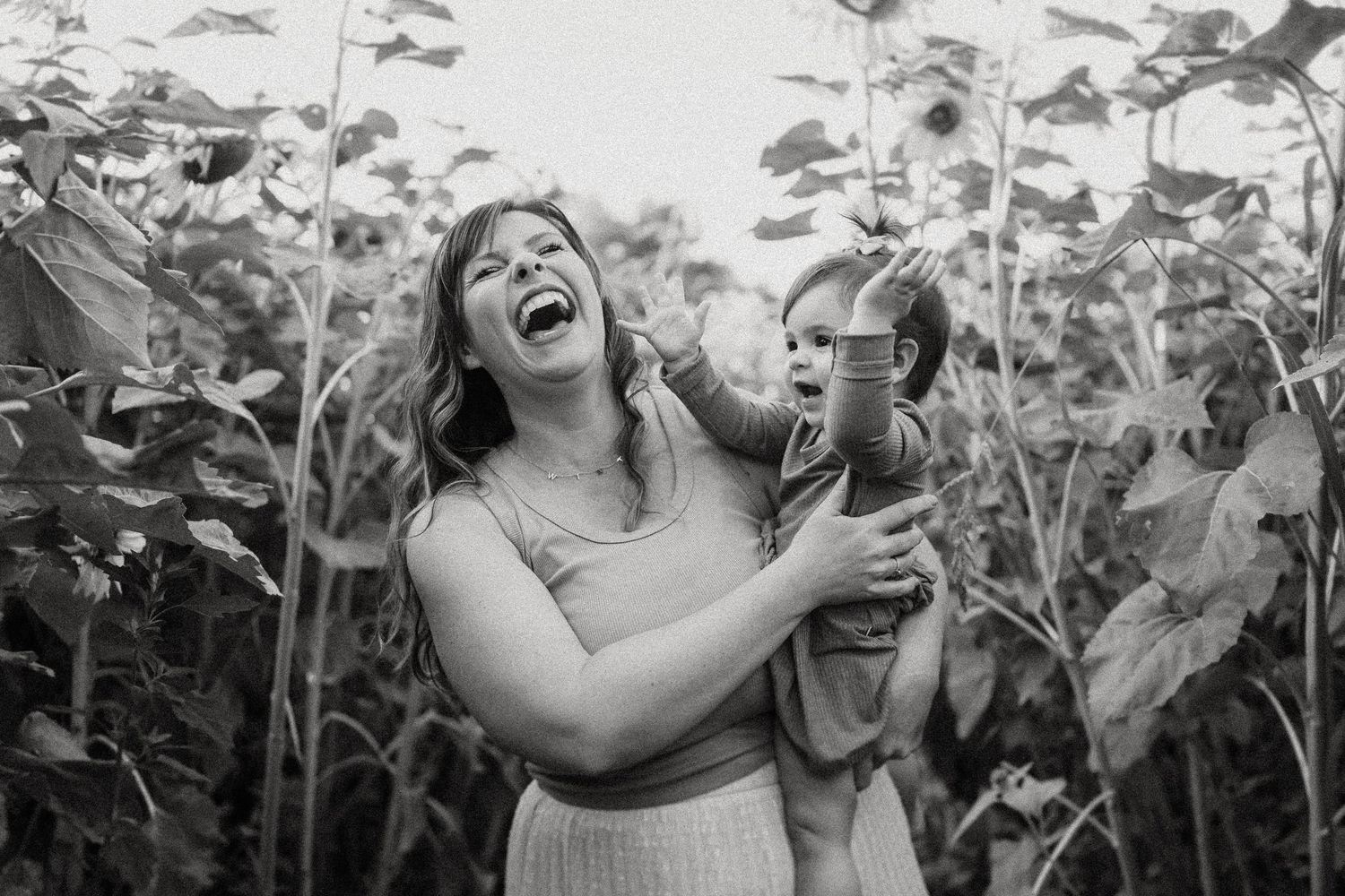 A joyful moment captured in black and white amongst towering sunflowers.